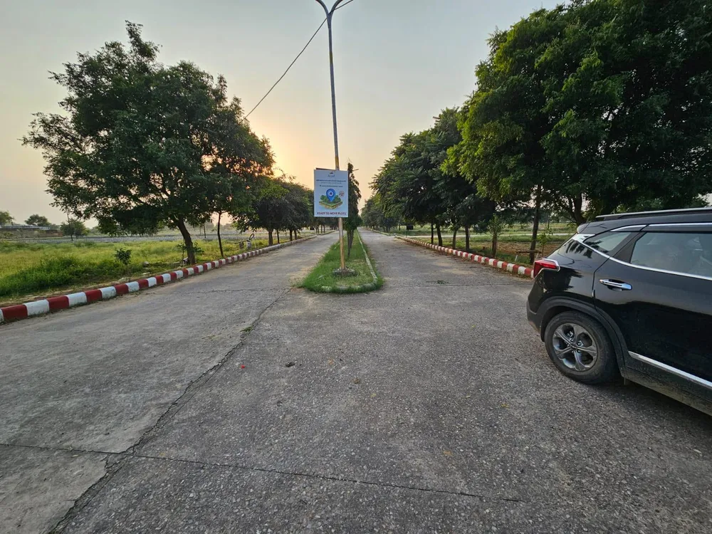 Concrete internal road with a kerbed central verge and avenue trees in Chanderlok City, Tijara