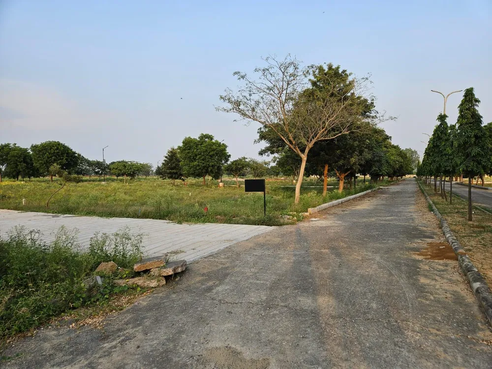 Open plot land beside a concrete internal road in Chanderlok City, Tijara
