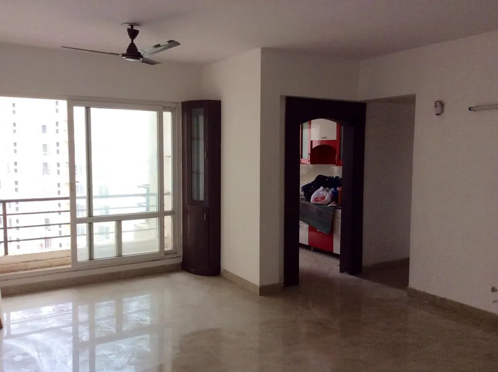 Hall with a corner display cabinet looking through an arched opening to the fitted kitchen, this 2 BHK flat at MVL Coral, Alwar Bypass Road, Bhiwadi