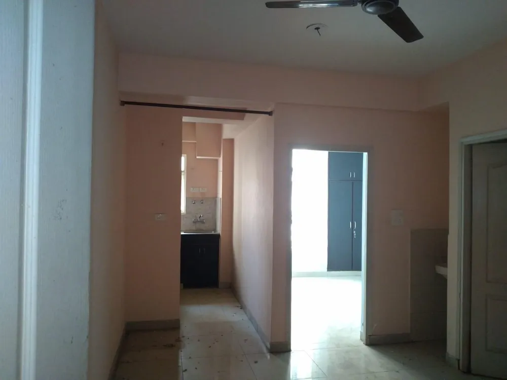 Hall with a ceiling fan looking through to the wash area and a bedroom doorway, this 2 BHK flat at MVL Coral, Alwar Bypass Road, Bhiwadi