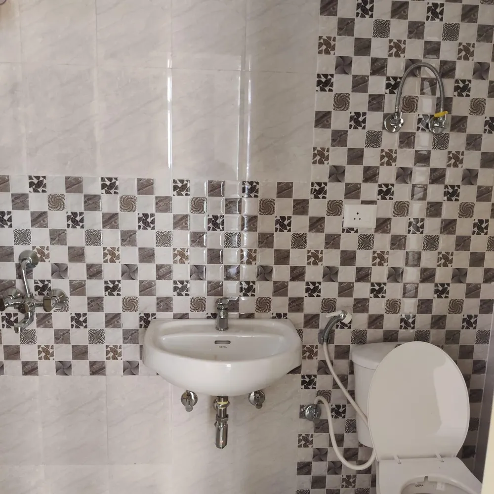 Bathroom with a wall-hung basin, mosaic feature tiling and marble-look wall tiles, this 3 BHK flat at MVL Coral, Alwar Bypass Road, Bhiwadi