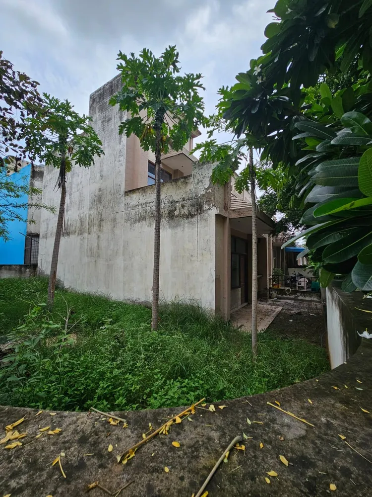 Two-storey house with plain plastered walls and an overgrown side ground in Omaxe Green Meadow City, Alwar Bypass Road, Bhiwadi