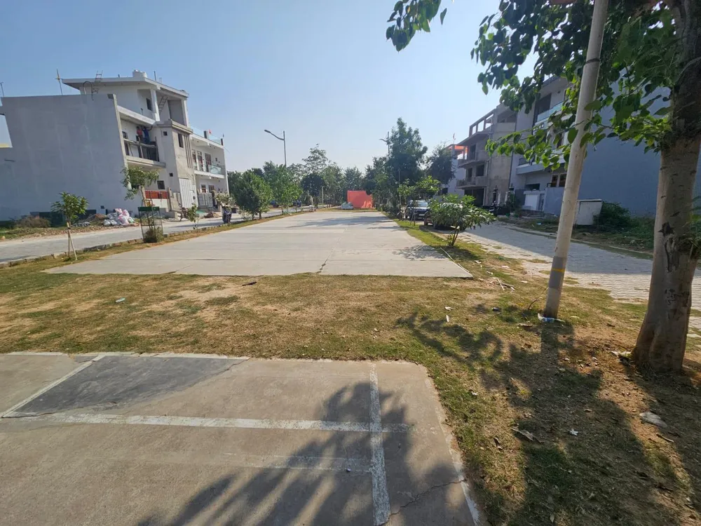 Concrete internal road with built houses and planted verges in Omaxe Green Meadow City, Alwar Bypass Road, Bhiwadi
