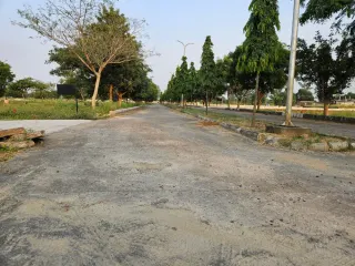 Concrete internal road running between plot rows in Chanderlok City, Tijara