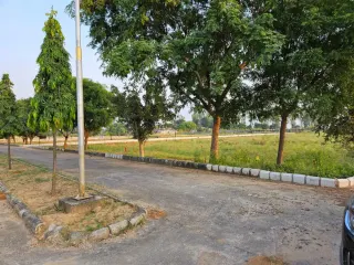 Tree-lined internal road with unbuilt plot land alongside in Chanderlok City