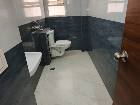 Bathroom with dark stone wall tiles and a wall-hung basin in a 5 BHK villa, Madhuvan Residency, Bhiwadi