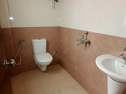 Tiled bathroom with a pedestal basin and health faucet in a Madhuvan Residency villa, Bhiwadi