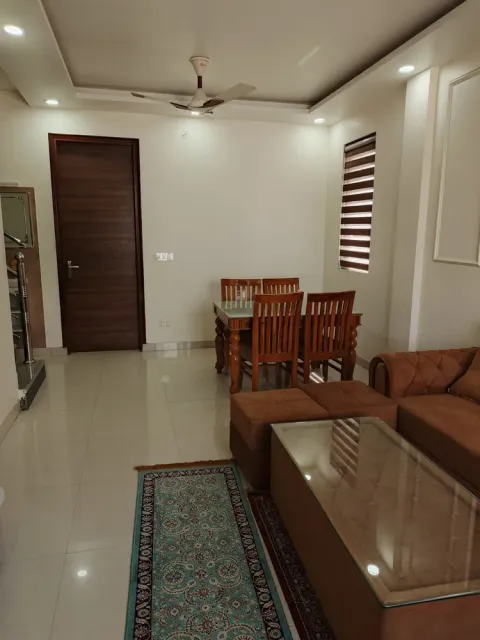 Dining area with a six-seat wooden table beside the living room of a Madhuvan Residency villa, Bhiwadi