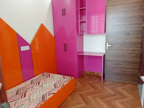 Children's room with orange and pink wall panels, a study desk and wardrobe in a Madhuvan Residency villa, Bhiwadi