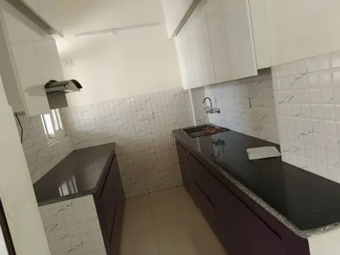 Modular kitchen with granite counter, chimney and white overhead cabinets in a Madhuvan Residency villa, Bhiwadi