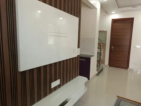 Wood-slat TV wall and hallway to the kitchen inside a 5 BHK villa in Madhuvan Residency, Bhiwadi