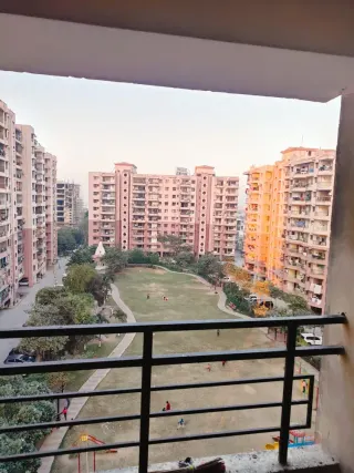 Balcony looking down over the central lawn and play area to the surrounding towers, this 2 BHK flat at MVL Coral, Bhiwadi