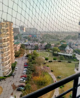 View from the balcony over the resident parking, the society park and the main road beyond, this flat at MVL Coral, Bhiwadi