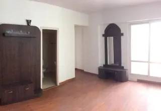 Bedroom with wooden flooring, a fitted wardrobe and a mirrored dressing table, this 3 BHK flat at MVL Coral, Alwar Bypass Road, Bhiwadi