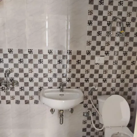 Bathroom with a wall-hung basin, mosaic feature tiling and marble-look wall tiles, this 3 BHK flat at MVL Coral, Alwar Bypass Road, Bhiwadi