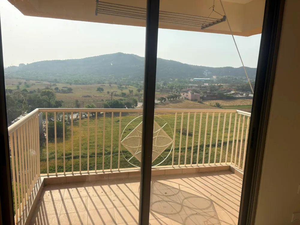 Balcony of an Ashiana Tarang flat in Bhiwadi looking across open fields to the Aravalli hills