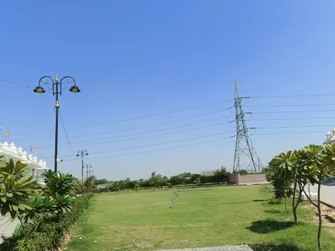 Open lawn with frangipani trees and street lamps inside Madhuvan Residency, Bhiwadi